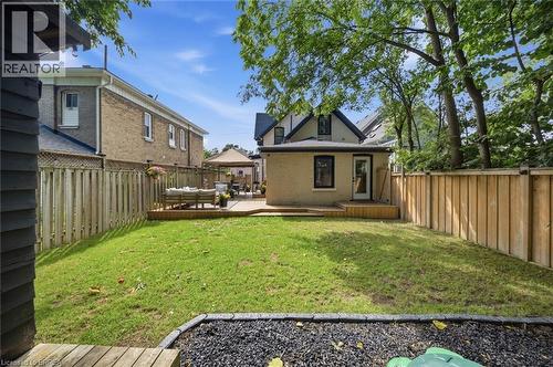 Expansive backyard featuring a manicured lawn, a raised wooden deck, and privacy fencing - 57 Terrace Hill Street, Brantford, ON 