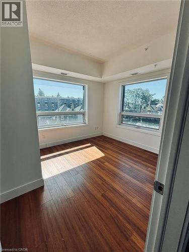 Wood-finish flooring, multiple large windows, and a tray ceiling feature prominently in this room - 1 Wellington Street Unit# 308, Brantford, ON 