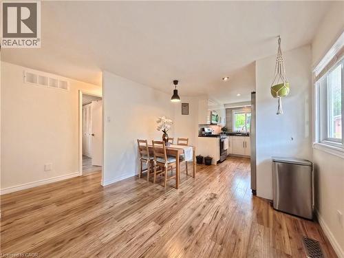 Wood-finish flooring throughout, recessed lighting, and a kitchen featuring white cabinetry, a stainless steel refrigerator, and a window with natural light - 380 Grangewood Drive, Waterloo, ON 