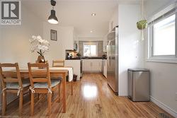 Kitchen featuring wood-finish flooring, white cabinetry, stainless steel appliances, and a tiled backsplash - 