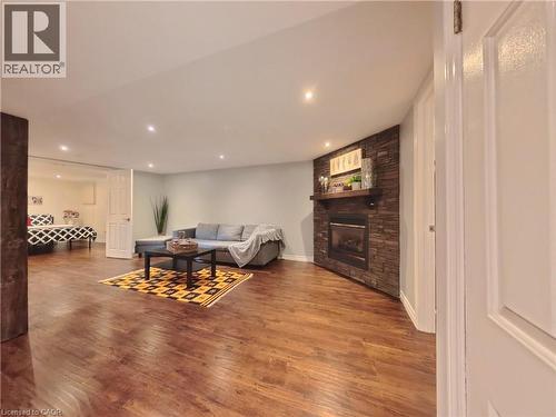 Wood-finish flooring throughout, featuring recessed lighting, a stone-clad fireplace with a wood mantle, and white interior doors - 380 Grangewood Drive, Waterloo, ON 