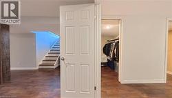 Wood-finish flooring, white paneled door, and recessed lighting - 