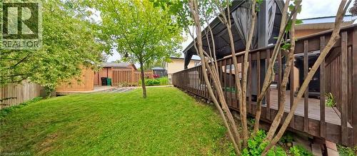Expansive backyard featuring a manicured lawn, established trees, and a wooden privacy fence - 380 Grangewood Drive, Waterloo, ON 