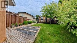 Expansive backyard featuring a manicured lawn, a full-width wood deck, and raised garden beds - 