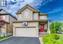 Two-story residential property featuring a brick and siding exterior, an attached two-car garage, a covered front porch with white columns, and a vibrant red entry door - 300 Watervale Crescent, Kitchener, ON 