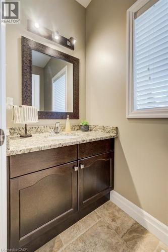 Modern vanity featuring a granite countertop, undermount sink, and wood-finish cabinetry with silver hardware - 300 Watervale Crescent, Kitchener, ON 