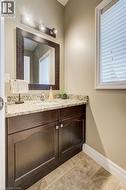 Modern vanity featuring a granite countertop, undermount sink, and wood-finish cabinetry with silver hardware - 