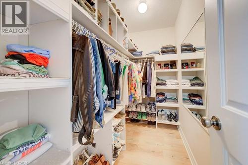 Walk-in closet featuring extensive built-in shelving, multiple hanging rods, dedicated shoe storage, a full-length mirror, and light wood-finish flooring - 300 Watervale Crescent, Kitchener, ON 