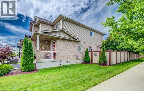 Exterior featuring brick and siding construction, covered front porch with white railing, paved driveway, mature trees, and a privacy fence - 300 Watervale Crescent, Kitchener, ON 