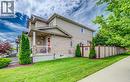Exterior featuring brick and siding construction, covered front porch with white railing, paved driveway, mature trees, and a privacy fence - 300 Watervale Crescent, Kitchener, ON 
