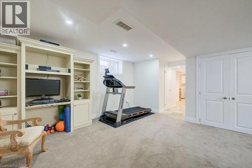 Lower-level room featuring built-in cabinetry with shelving, recessed lighting, a window, and a door leading to an adjacent area with tile flooring - 300 Watervale Crescent, Kitchener, ON 