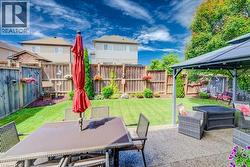 Expansive backyard featuring a manicured lawn, established landscaping, and a privacy fence - 