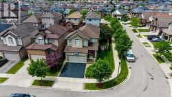 Suburban residence featuring a two-story exterior, attached garage with a paved driveway, mature trees, and a manicured lawn - 