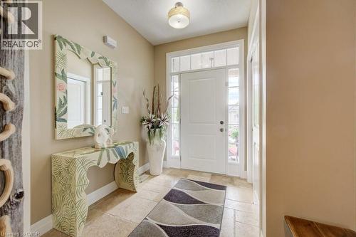 Entryway featuring a white paneled door with sidelights and transom window, light-toned stone-finish flooring, and a flush-mount ceiling light fixture - 300 Watervale Crescent, Kitchener, ON 