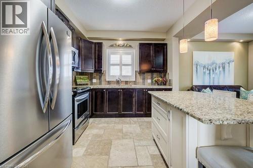 Kitchen featuring a stainless steel French-door refrigerator, dark wood-finish cabinetry, and a light-toned tile backsplash - 300 Watervale Crescent, Kitchener, ON 