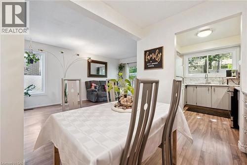 Open-concept design featuring wood-finish flooring, white walls, and a recessed kitchen area with a window and light-toned cabinetry - 46 Cedarwoods Crescent Unit# 53, Kitchener, ON - Indoor