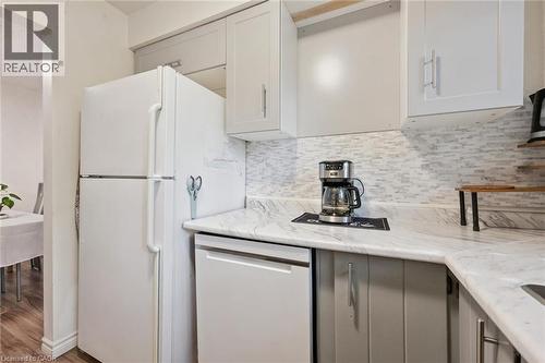Kitchen featuring light gray upper cabinetry and contrasting lower cabinetry, white marbled countertops, and a full tile backsplash - 46 Cedarwoods Crescent Unit# 53, Kitchener, ON - Indoor Photo Showing Kitchen