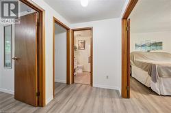 Wood-finish flooring throughout, white painted walls, and wood-trim doorways - 