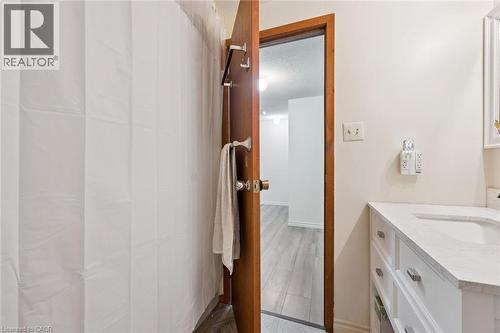 White vanity with a single basin, light-toned countertop, and chrome hardware - 46 Cedarwoods Crescent Unit# 53, Kitchener, ON - Indoor Photo Showing Bathroom