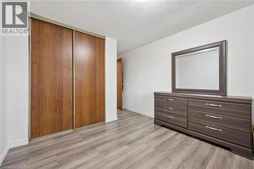 Wood-finish flooring with a neutral white wall color, featuring a built-in closet with sliding wood-finish doors - 46 Cedarwoods Crescent Unit# 53, Kitchener, ON - Indoor Photo Showing Other Room