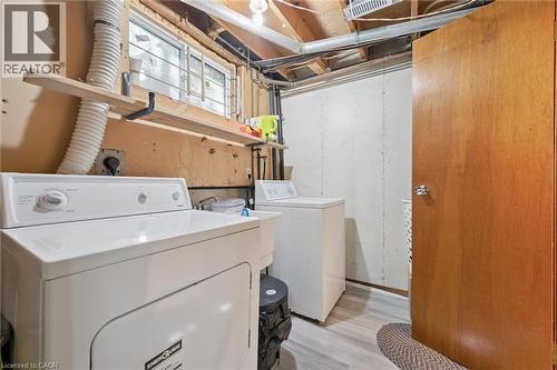 Functional laundry area featuring a utility sink, a window, and wood-finish flooring - 46 Cedarwoods Crescent Unit# 53, Kitchener, ON - Indoor Photo Showing Laundry Room