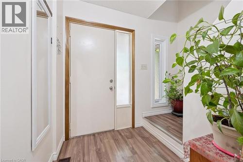 Entryway featuring wood-finish flooring, a white entry door with a frosted sidelight, and a narrow vertical window - 46 Cedarwoods Crescent Unit# 53, Kitchener, ON - Indoor Photo Showing Other Room