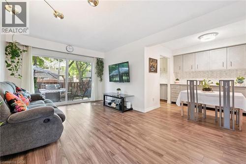 Wood-finish flooring throughout, sliding glass door with backyard access, kitchen with light-toned cabinetry, tile backsplash, and recessed lighting - 46 Cedarwoods Crescent Unit# 53, Kitchener, ON - Indoor Photo Showing Living Room