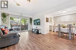 Wood-finish flooring throughout, sliding glass door with backyard access, kitchen with light-toned cabinetry, tile backsplash, and recessed lighting - 