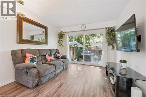Wood-finish flooring, sliding glass patio doors, and a mounted overhead light fixture - 46 Cedarwoods Crescent Unit# 53, Kitchener, ON - Indoor Photo Showing Living Room