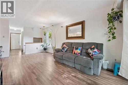 Wood-finish flooring throughout, a large window providing natural illumination, and a partial wall with a wood-stained cap - 46 Cedarwoods Crescent Unit# 53, Kitchener, ON - Indoor Photo Showing Living Room