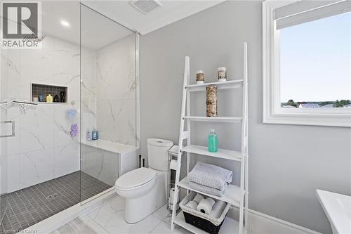 Glass-enclosed shower with a built-in bench, recessed niche, rainfall showerhead, and contrasting floor tiles - 2312 Ridgeview Court, Burlington, ON - Indoor Photo Showing Bathroom