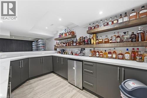 Built-in wet bar with dark cabinetry, integrated beverage refrigerator, light countertops, and wood-finish open shelving - 2312 Ridgeview Court, Burlington, ON - Indoor