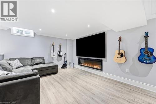 Recessed lighting, wood-finish flooring, a wall-mounted electric fireplace, and a window for natural light - 2312 Ridgeview Court, Burlington, ON - Indoor Photo Showing Living Room With Fireplace