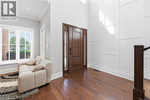 Hardwood-finish flooring throughout, solid wood entry door with glass sidelights, tall ceilings, recessed lighting, and decorative wall paneling - 2312 Ridgeview Court, Burlington, ON - Indoor Photo Showing Other Room