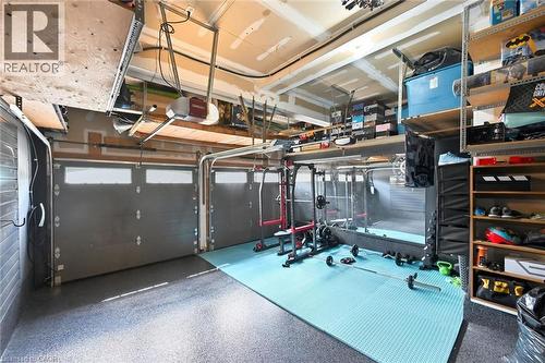 Garage space featuring a two-car capacity, epoxy flooring, overhead storage shelving, and built-in wall shelving - 2312 Ridgeview Court, Burlington, ON - Indoor Photo Showing Garage