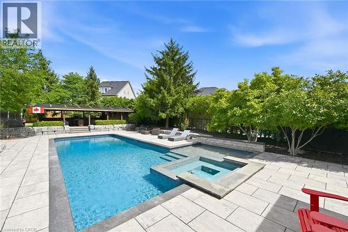Expansive outdoor living area featuring a rectangular swimming pool, integrated spa, and light-toned paver decking - 2312 Ridgeview Court, Burlington, ON - Outdoor With In Ground Pool With Deck Patio Veranda With Backyard