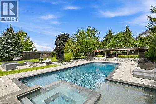 Expansive backyard featuring a large swimming pool with integrated spa, extensive paver patio, a covered outdoor structure, and a dedicated fire pit area - 2312 Ridgeview Court, Burlington, ON - Outdoor With In Ground Pool With Backyard