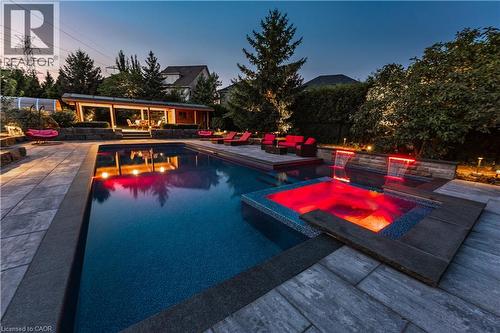 Expansive backyard featuring a large swimming pool, integrated spa, and a covered outdoor living structure - 2312 Ridgeview Court, Burlington, ON - Outdoor With In Ground Pool With Deck Patio Veranda
