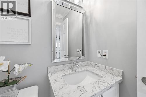 Vanity with a white undermount sink and a stone-finish countertop, complemented by a framed mirror and chrome faucet - 2312 Ridgeview Court, Burlington, ON - Indoor Photo Showing Bathroom