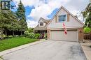 Gabled residence featuring brick and siding facade, a double-bay garage with overhead lighting, and a paved driveway - 4248 Dunvegan Road, Burlington, ON 