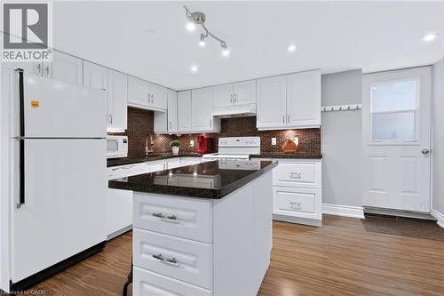 White cabinetry, dark countertops, a kitchen island, wood-finish flooring, and recessed lighting - 4248 Dunvegan Road, Burlington, ON 