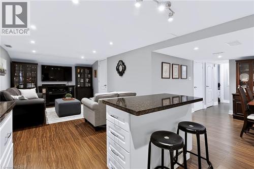 Open-concept living space with wood-finish flooring, recessed lighting, and a kitchen island featuring a dark countertop - 4248 Dunvegan Road, Burlington, ON 
