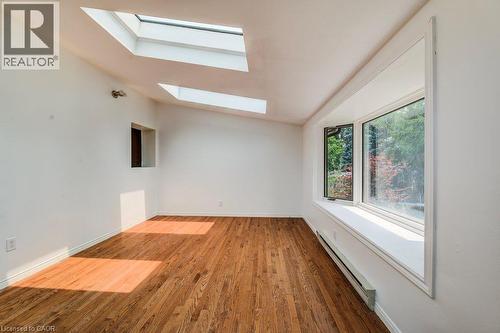 Wood-finish flooring with a bay window and skylights - 109 White Oak Place, Waterloo, ON - Indoor Photo Showing Other Room