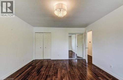 Dark wood-finish flooring, bi-fold closet doors, and a ceiling light. - 109 White Oak Place, Waterloo, ON - Indoor Photo Showing Other Room