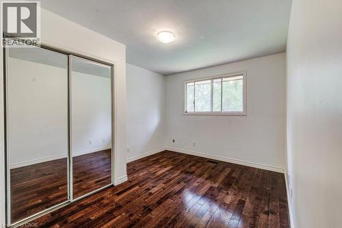 Rich wood-finish flooring, mirrored closet doors, a single window, and ceiling light - 109 White Oak Place, Waterloo, ON - Indoor Photo Showing Other Room