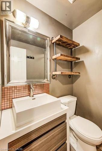 Vessel sink with a  wood-finish vanity and mosaic tile backsplash. - 109 White Oak Place, Waterloo, ON - Indoor Photo Showing Bathroom