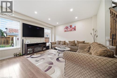 Recessed ceiling lighting, wood-finish flooring, white wall paint, white window frames, and wood staircase railing - 57 Cheevers Road, Brantford, ON - Indoor Photo Showing Living Room