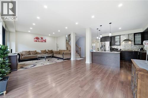 Recessed lighting throughout, wood-finish flooring, kitchen island with pendant lighting, stainless steel appliances, and a tiled kitchen backsplash - 57 Cheevers Road, Brantford, ON - Indoor Photo Showing Other Room
