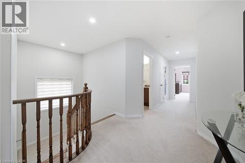 Curved wood-finish railing, recessed ceiling lighting, light-toned carpeting, and multiple doorways - 57 Cheevers Road, Brantford, ON - Indoor Photo Showing Other Room