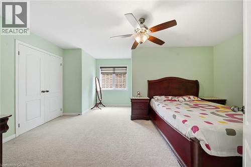 Wall-to-wall carpeting with a ceiling fan light fixture, window with blinds, and white bi-fold closet doors - 57 Cheevers Road, Brantford, ON - Indoor Photo Showing Bedroom